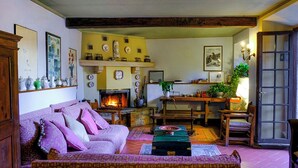 Una sala acogedora con chimenea, un sofá, una mesa de comedor y varios objetos decorativos.