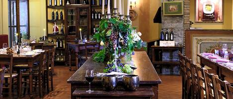 Un restaurante con una larga mesa de madera, copas de vino y una variedad de botellas en estanterías.