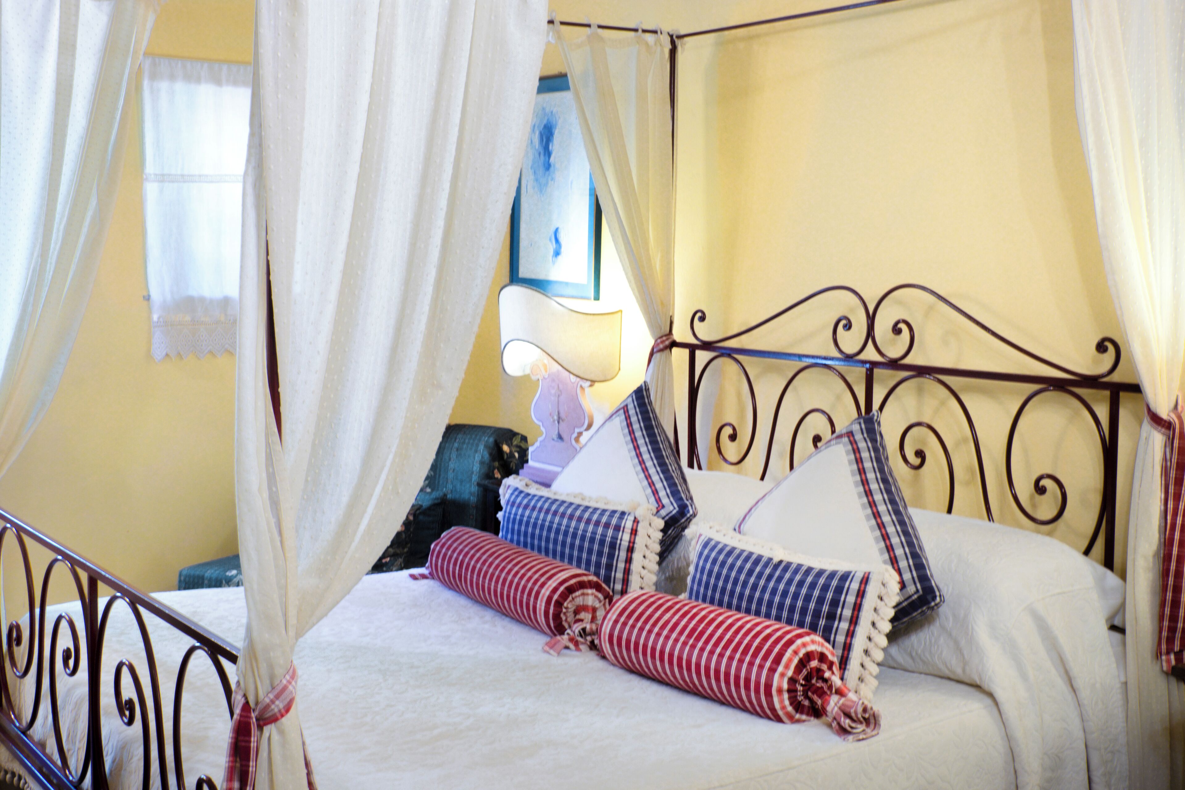 A bed with a canopy, pillows, and a blanket.