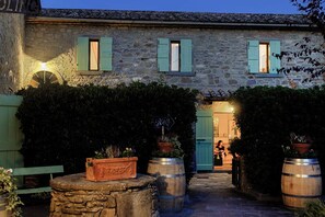 Un edificio de piedra con encanto rústico, que presenta una entrada acogedora y un pequeño espacio al aire libre para sentarse.