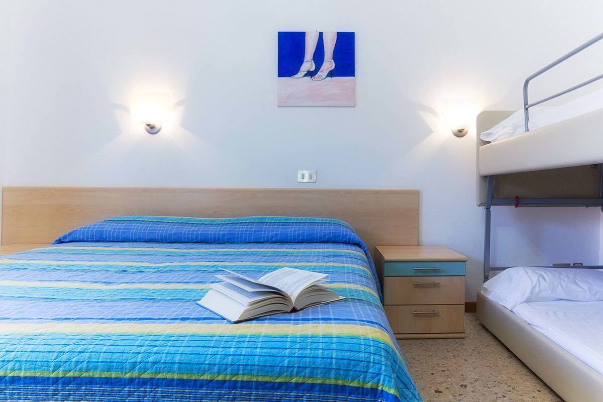 Een kamer met een bed, een nachtkastje, een tweepersoonsbed en een schilderij aan de muur.
