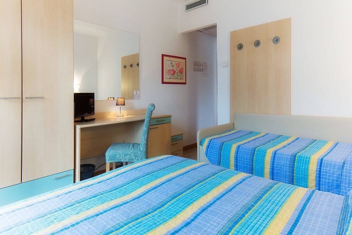 Een slaapkamer met twee bedden, een bureau, een stoel en een spiegel.