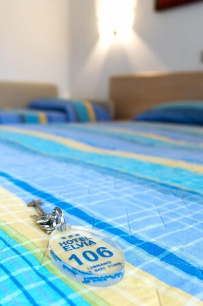 A bed with a checkered bedspread and a keychain with a hotel name and number. - Hotel Elvia (Lignano Sabbiadoro)