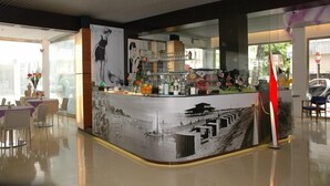 A bar area with a counter displaying various bottles and glasses, a mural of a beach scene, and a stop sign visible through the window.