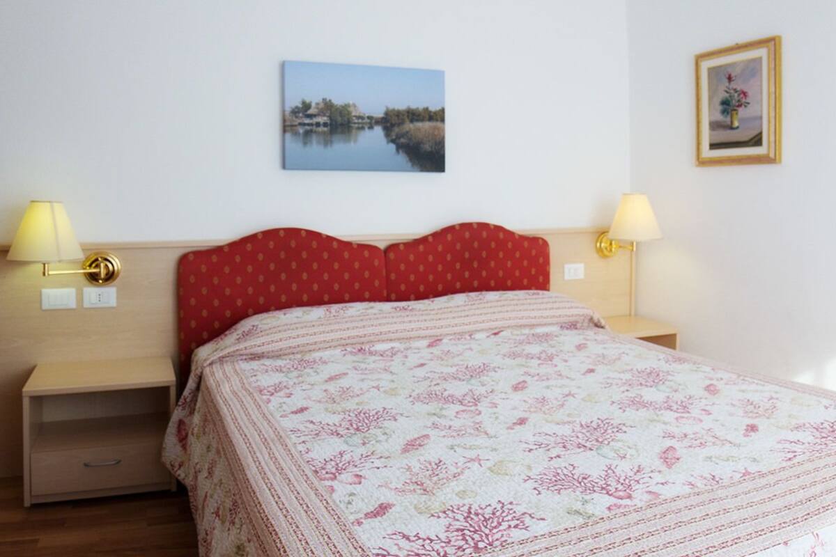 Een verzorgde hotelkamer met een bed, twee nachtkastjes en wandlampen.