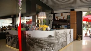 A reception desk with a large mural depicting a historical scene, a modern pendant light, and a red column.