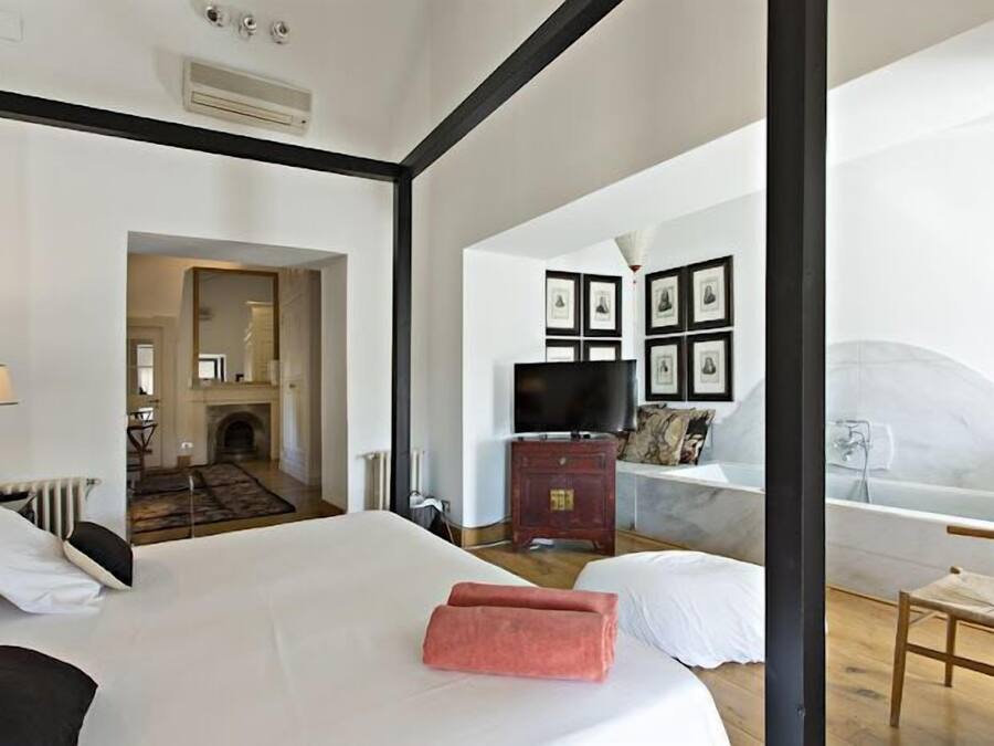 Habitación de hotel con una cama grande, televisión, chimenea y vistas al exterior.