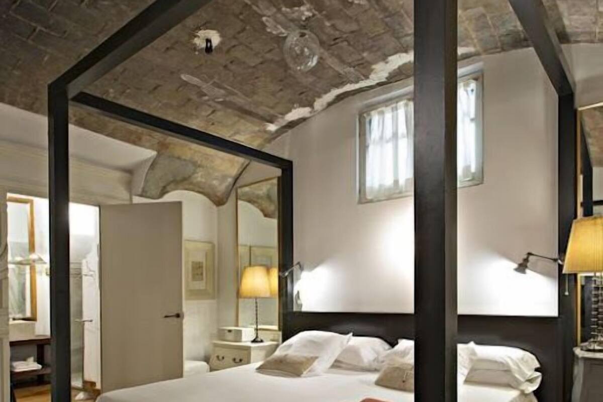 A bedroom with a large bed, a wooden floor, and a brick ceiling.