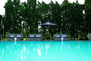 Une piscine avec des chaises longues et des parasols.