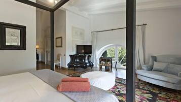 A hotel room with a bed, a sofa, a TV, and a view of the outdoors.