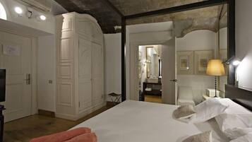 A hotel room with a large bed, white wardrobe, and a mirror with a lamp.