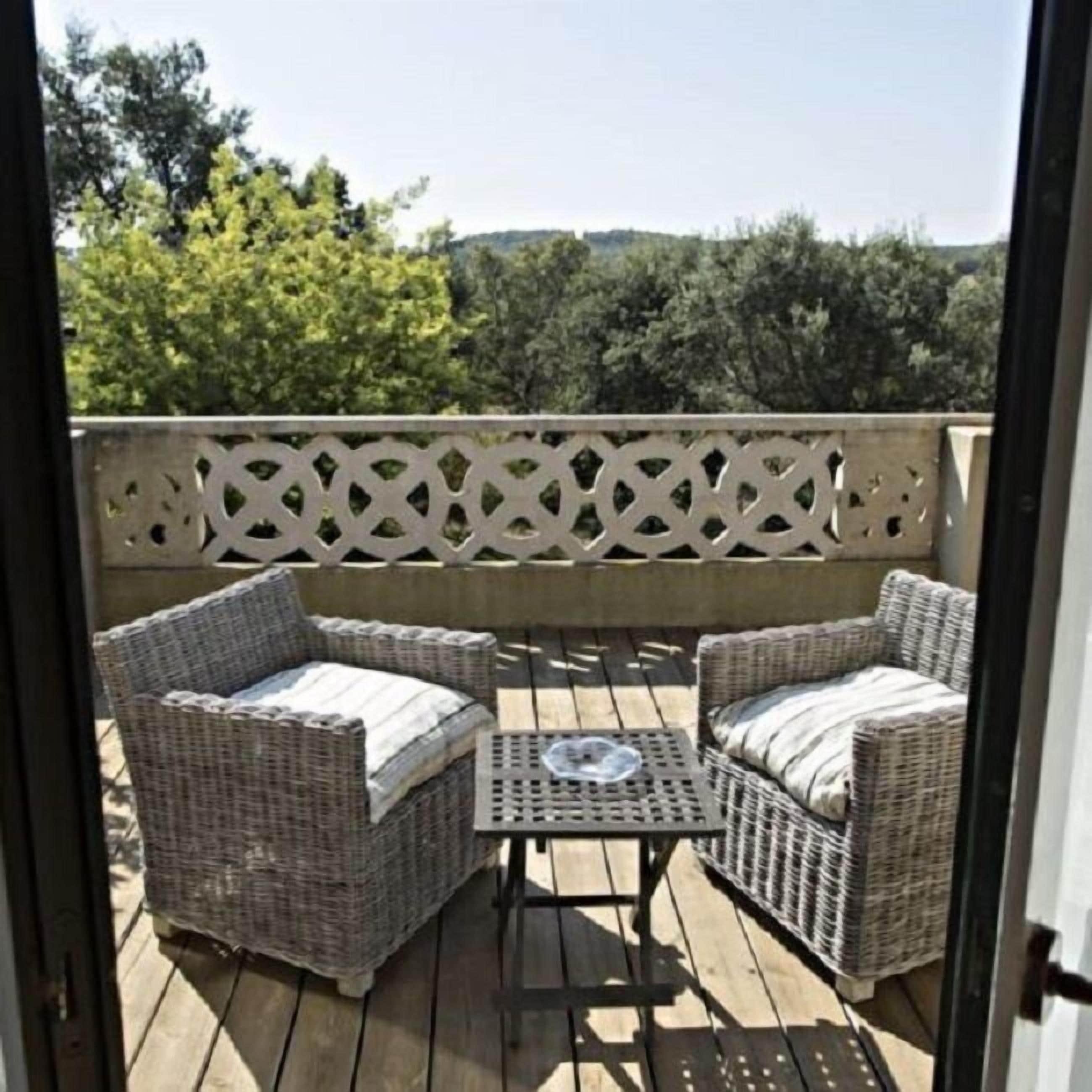 A balcony with wicker furniture, including two chairs and a small table.