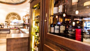 Una zona de bar con mostrador de madera y estantes llenos de botellas de vino.
