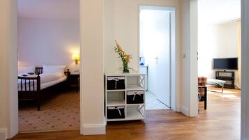 Een hotelkamer met een bed, nachtkastje, lamp, opbergruimte en een televisie in de aangrenzende zithoek.