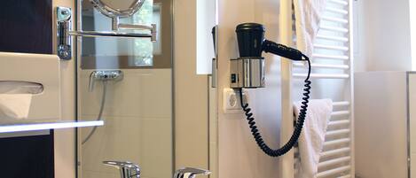 Un baño moderno con un lavamanos blanco, un espejo y un perchero para toallas.
