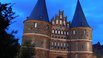 A historic building with two prominent towers, a central arched entrance, and a brick facade.
