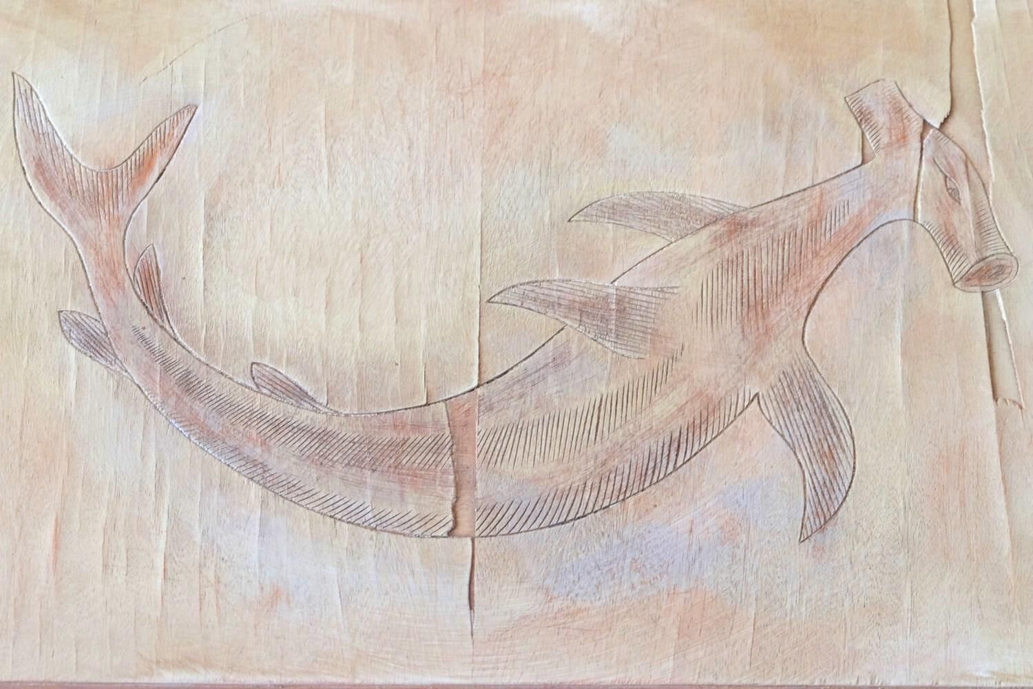 A wooden surface with a carved fish design.