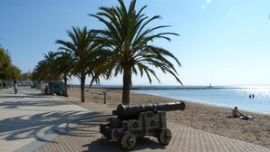 Un canon est placé sur une promenade pavée, au bord de la plage.