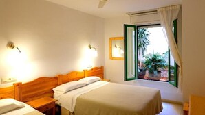 Une chambre à coucher avec un lit, des tables de chevet, un ventilateur de plafond et une fenêtre avec des rideaux.