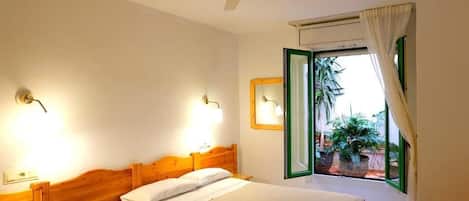 A bedroom with a bed, bedside tables, a ceiling fan, and a window with curtains.