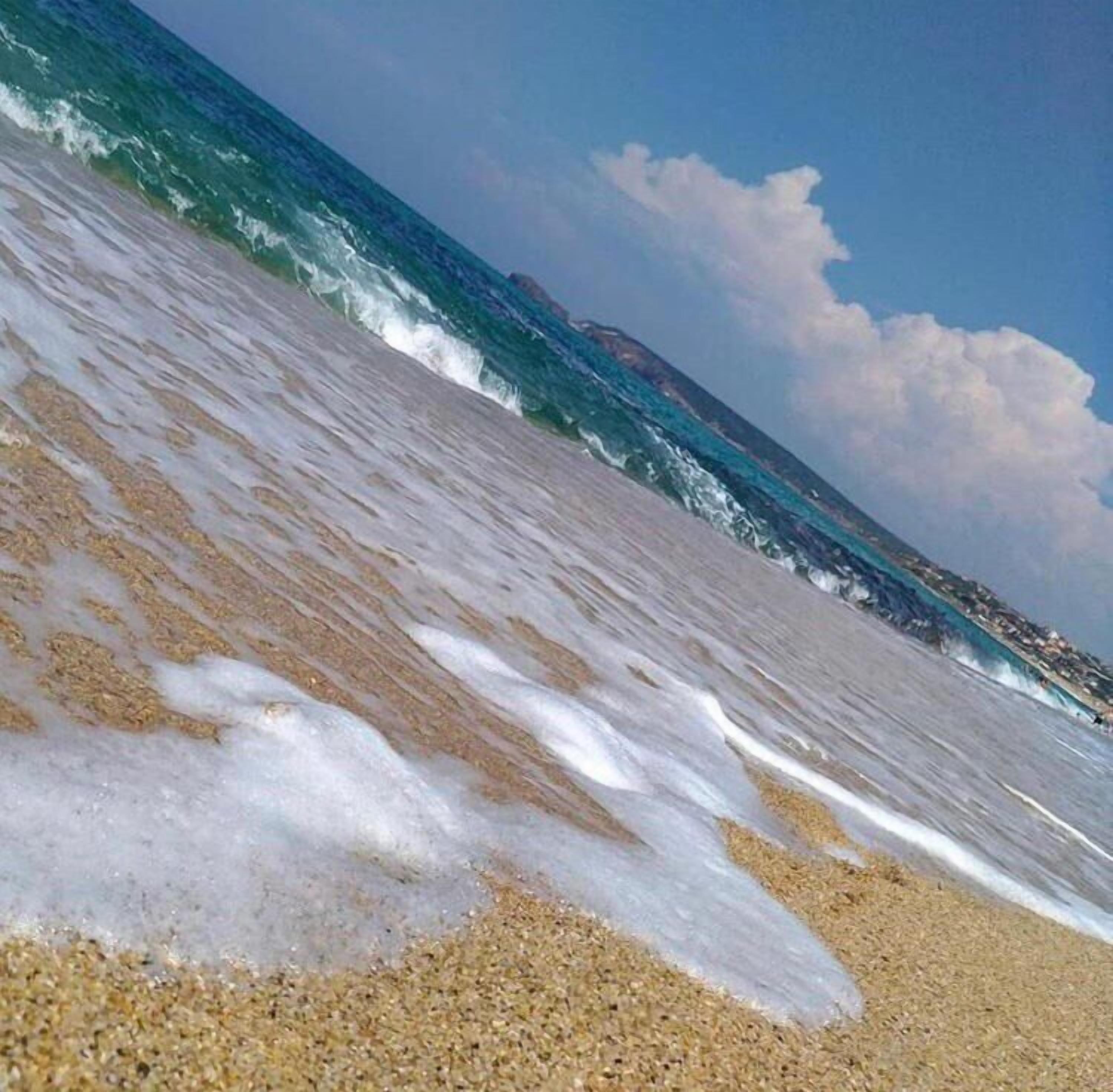 A beach with waves approaching the shore.