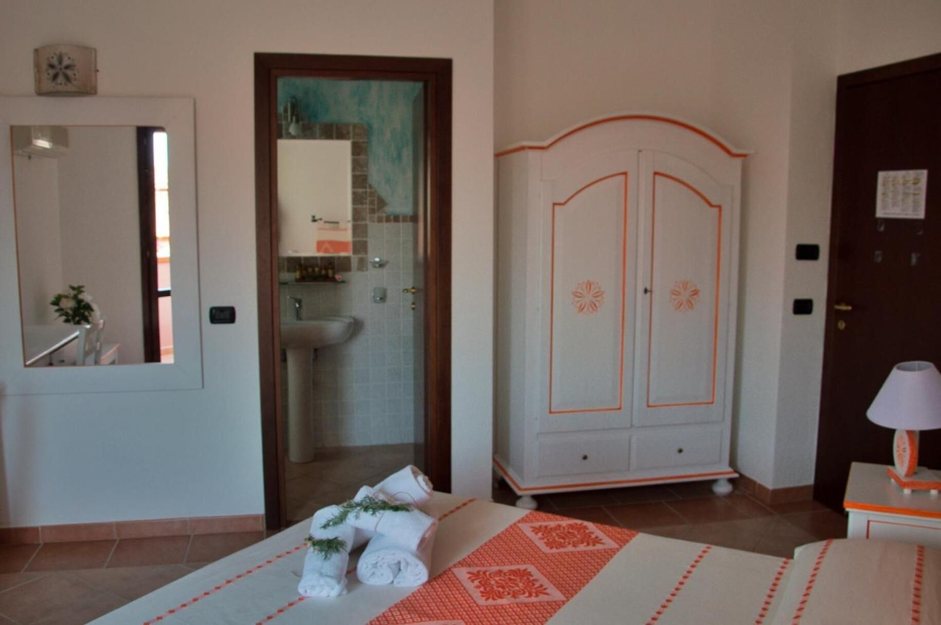 Ein Hotelzimmer mit Bett, Badezimmer mit Waschbecken, Kleiderschrank und Spiegel.