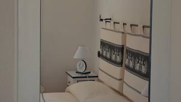 A bedroom with a bed, a nightstand, a lamp, and a mirror.