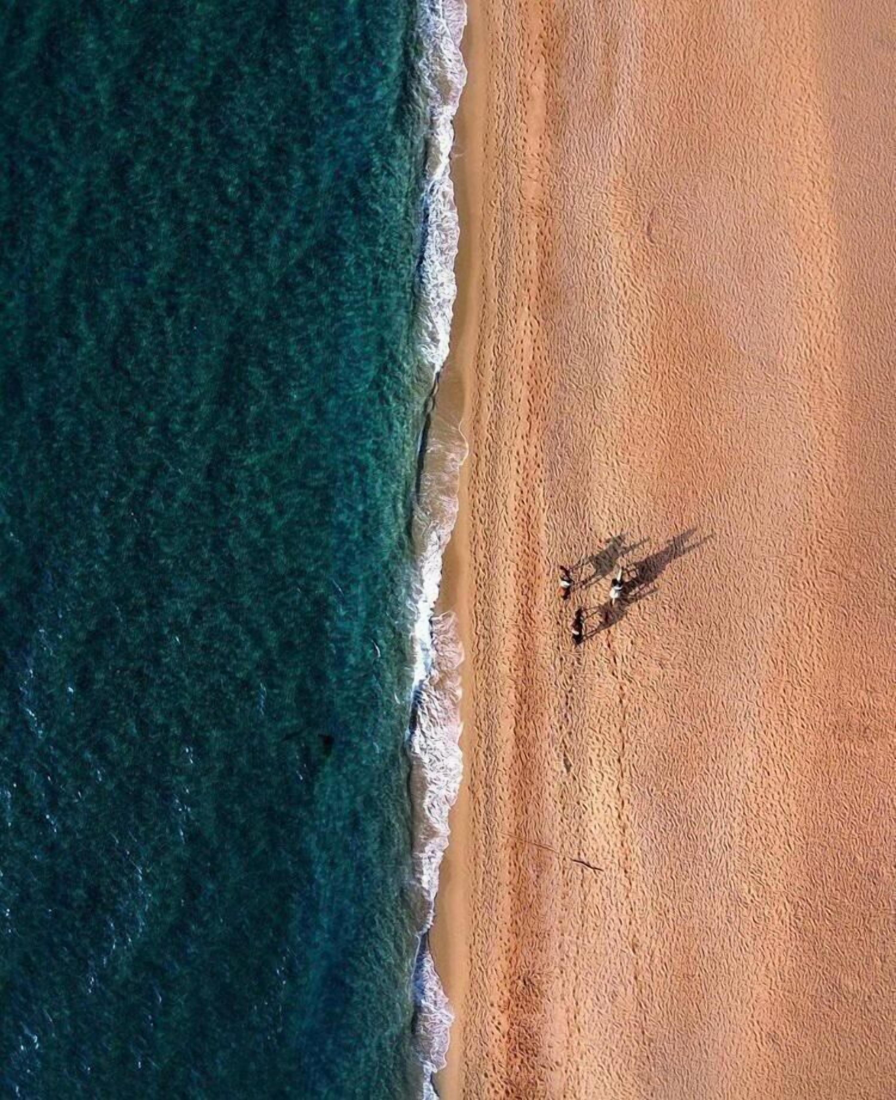 Vista aérea de una playa con agua turquesa cristalina y una orilla arenosa.