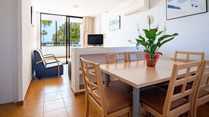 Un coin repas avec une table et des chaises en bois, un téléviseur fixé au mur et une plante en pot.