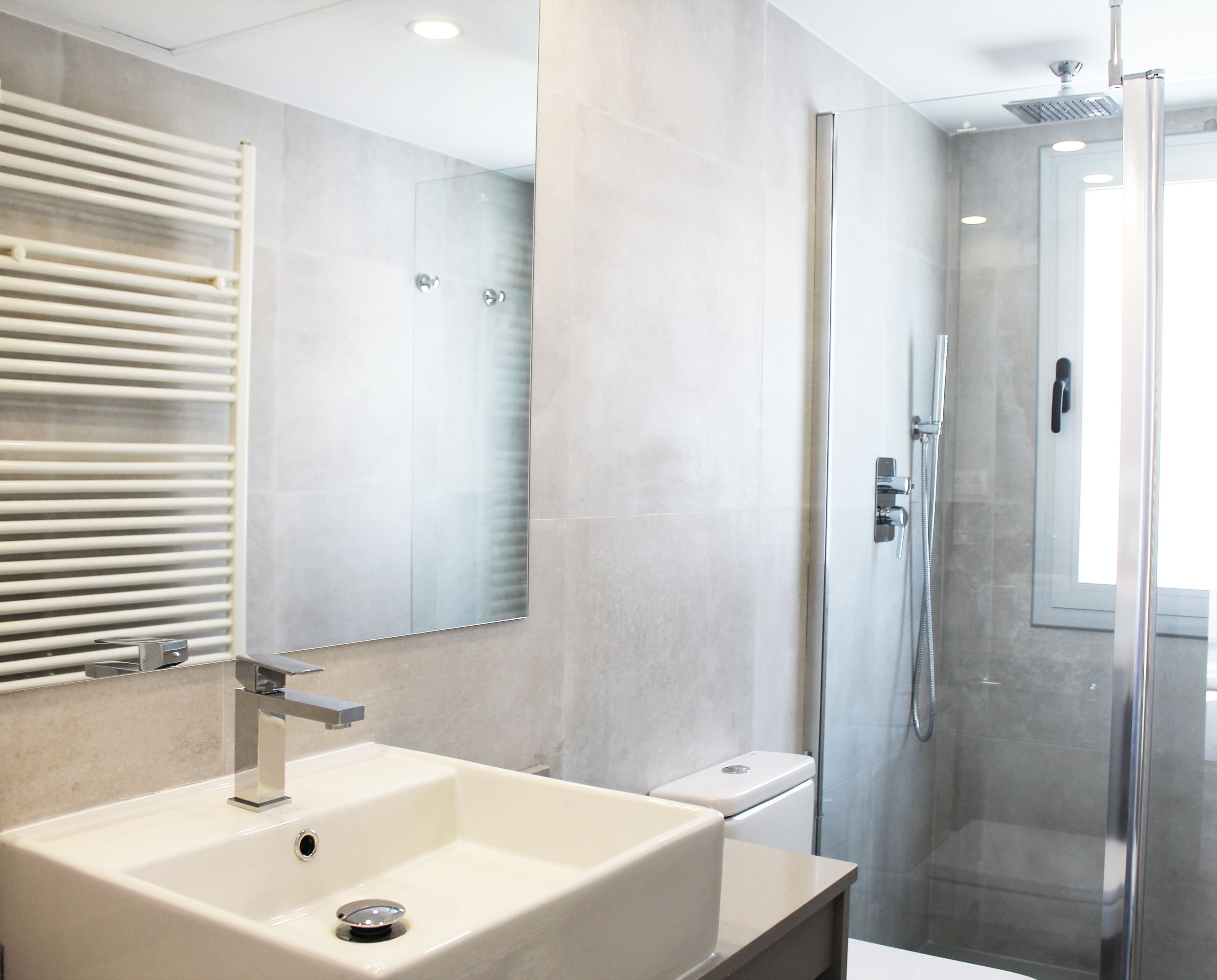 A modern bathroom with a large sink, a glass shower enclosure, and a toilet.
