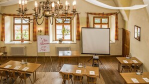 Une salle de conférence équipée de tables et de chaises en bois, d’un tableau blanc et d’un écran de projection.
