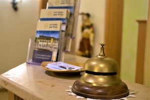 A reception area with a wooden counter, a brass bell, and informational brochures. - Hotel Gasthof zum Bräu (Kinding)