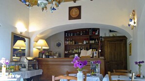Een eetgedeelte met gedekte tafels, een bar met flessenkasten en een houten kast.
