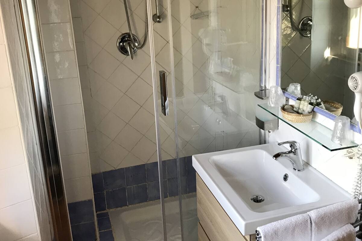 A bathroom with a glass-enclosed shower, a white sink, and a mirror above it.