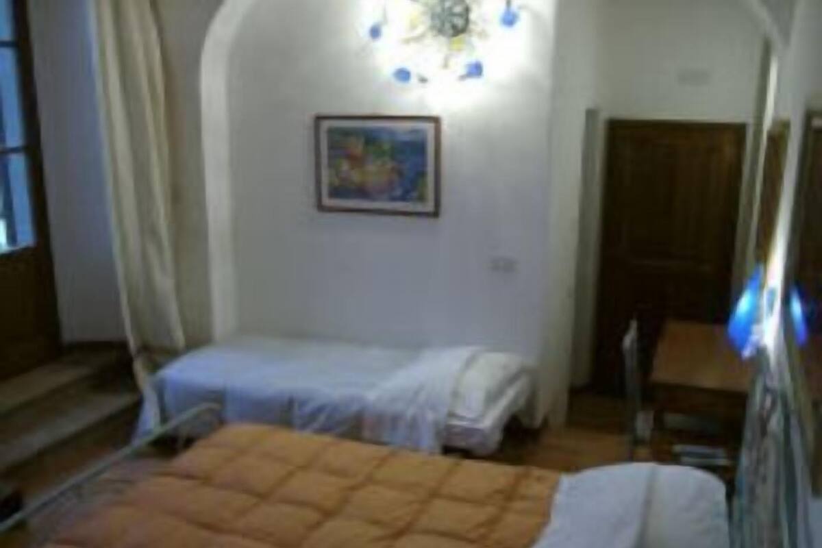 A bedroom with two beds, a staircase, and a painting on the wall.
