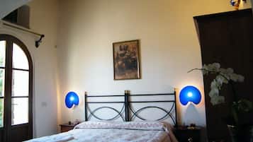 A bedroom with a bed, two wall-mounted lamps, a painting on the wall, and a potted orchid.