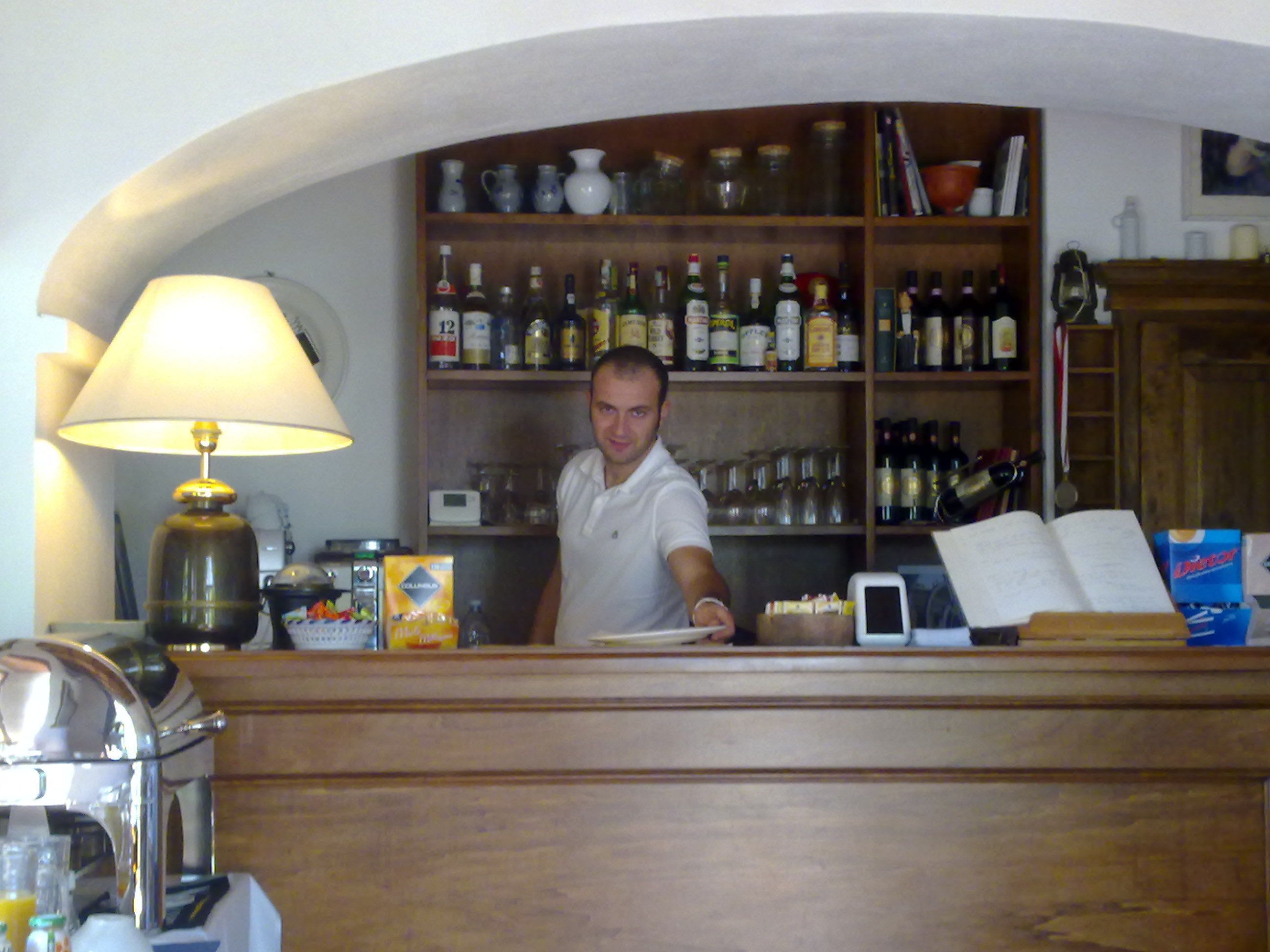 A bar area with a counter, a lamp, and shelves stocked with bottles.
