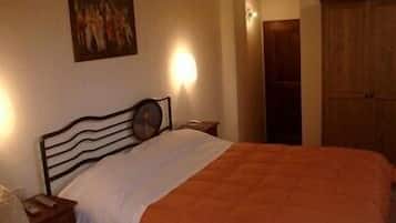 A bedroom with a bed, a nightstand, a wall-mounted painting, and a wooden wardrobe.