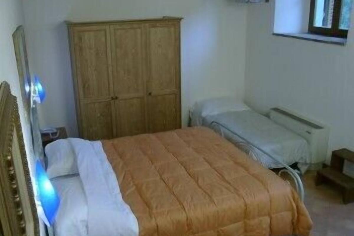 A bedroom with a bed, a wardrobe, and a window.
