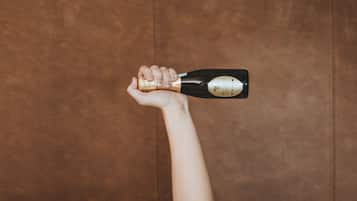 A person lying in bed with a bottle of champagne.
