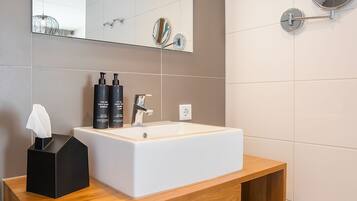 Een moderne badkamer met een witte wastafel, een houten wastafelmeubel en een grote spiegel.