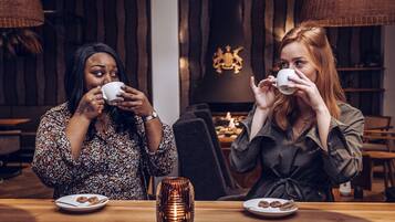 Dos personas sentadas en una mesa de madera con platos de galletas y una vela.