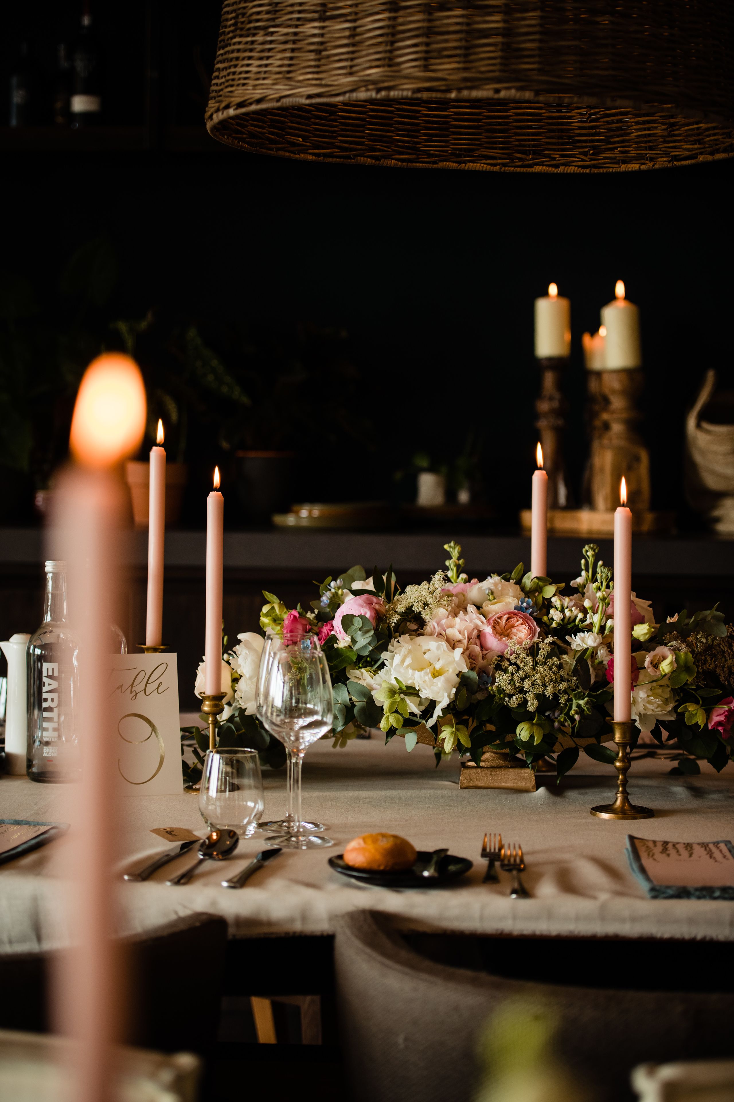 A table set with candles, flowers, and glassware, suggesting a romantic or intimate dining setting.