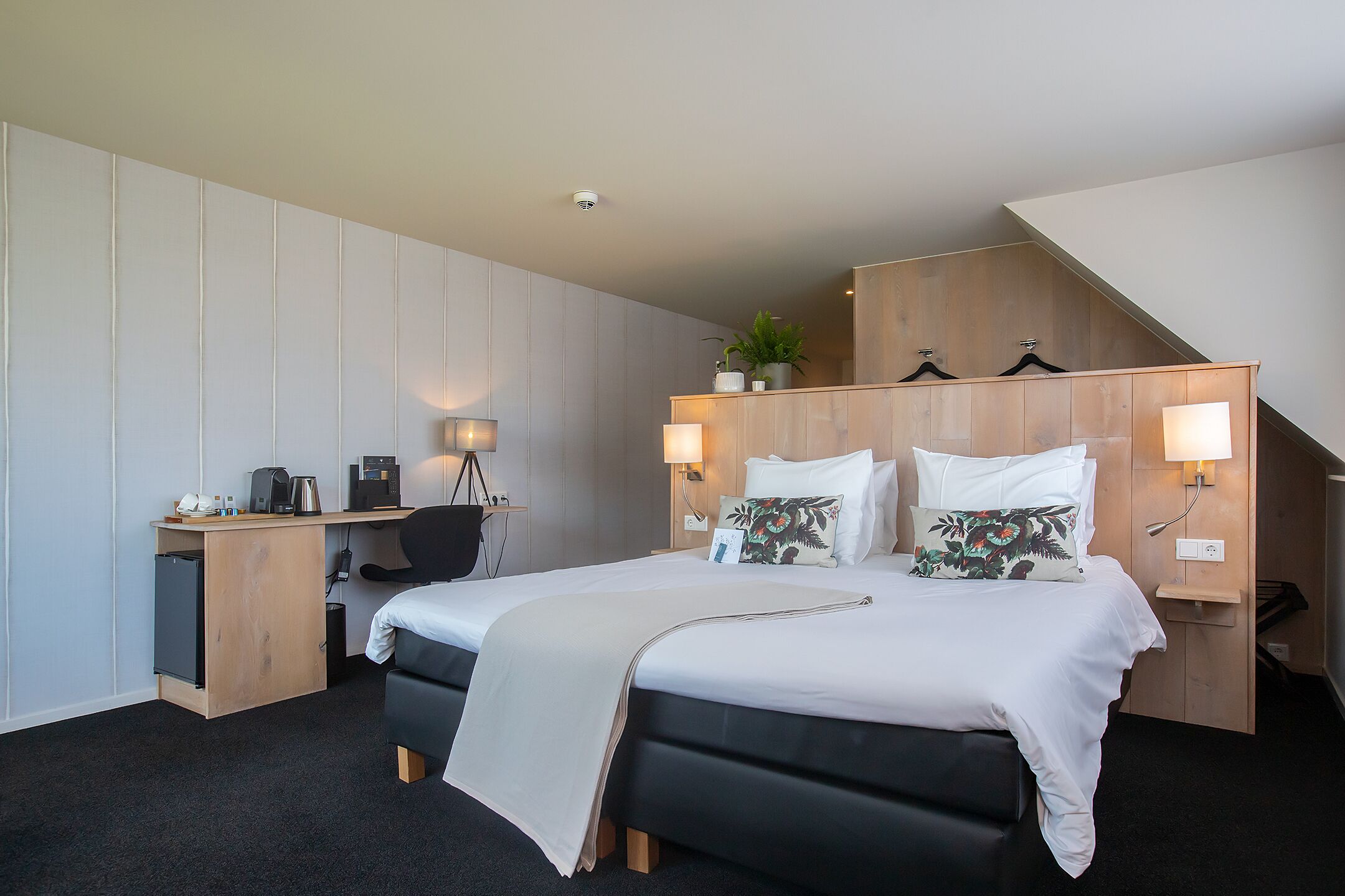 A hotel room with a bed, desk, and chair.