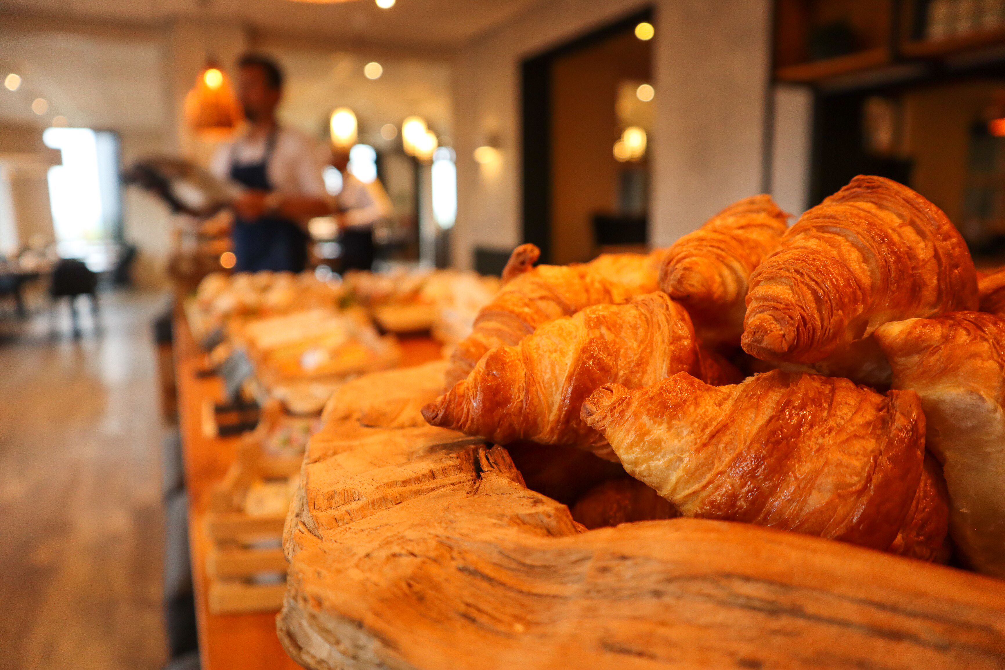 Eine Bäckertheke mit Croissants und einer Person im Hintergrund.