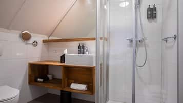 A modern bathroom with a shower, toilet, and wooden shelves with toiletries.