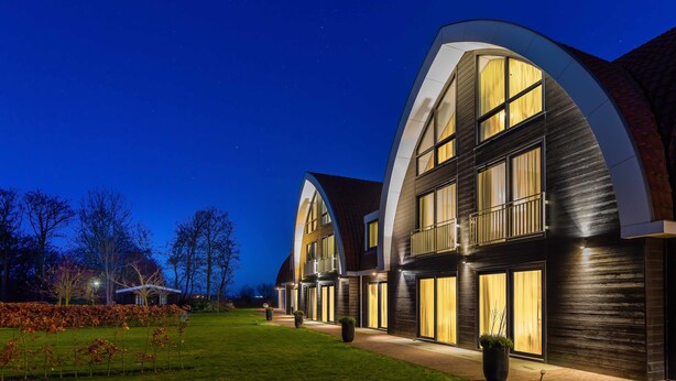 Ein modernes Hotel mit einer gewölbten Fassade, großen Fenstern und einem gut beleuchteten Eingang.