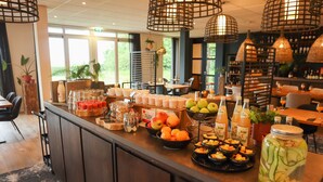 Ein Frühstücksbuffet mit Früchten, Säften und einem großen Einweckglas eingelegtes Gemüse.
