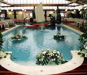 Una piscina interior decorada con un velero y arreglos florales.
