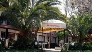 A building with a sign reading "RESIDENCIAL" and a covered entrance area with a palm tree in the foreground. - Hotel João Capela (Aveiro)